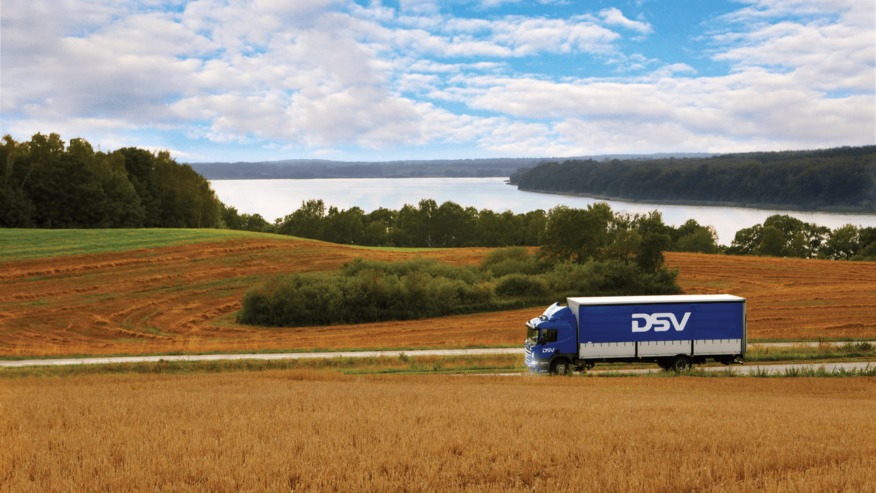 DSV-lastebil kjører langs kornmarker.
